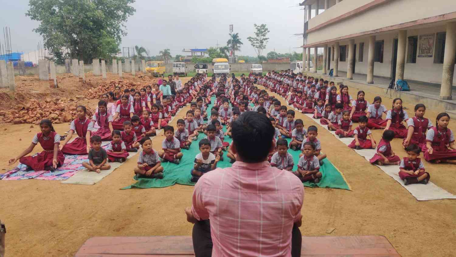 विद्यालय परिसर में शिक्षक द्वारा विद्यार्थियों को योग अभ्यास सिखाते हुए